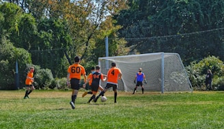 group of children playing soccer on green grass field during daytime