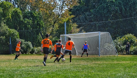 group of children playing soccer on green grass field during daytime