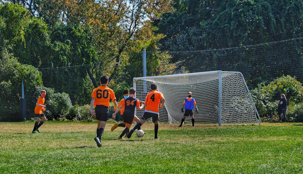 grupo de niños jugando al fútbol en el campo de hierba verde durante el día