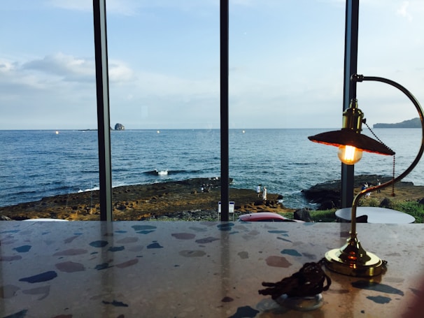 A ceramic table lamp with soft blue glaze casting a cozy light on a seaside cottage table