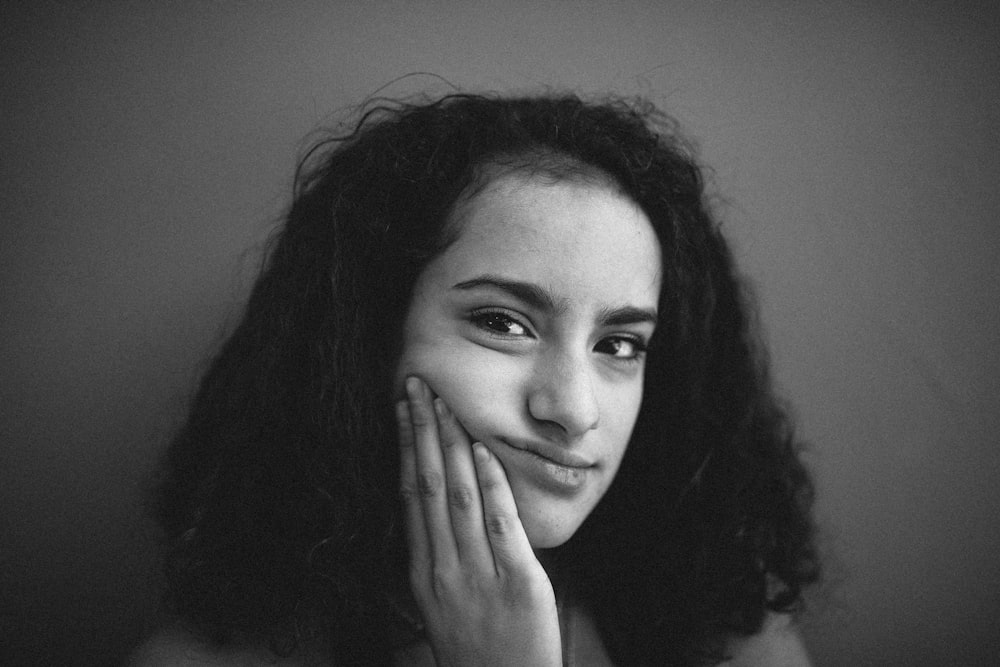 grayscale photo of woman with left hand on her face