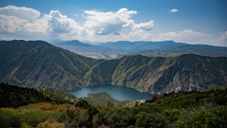 A picturesque view of a lake surrounded by lush greenery and hills.