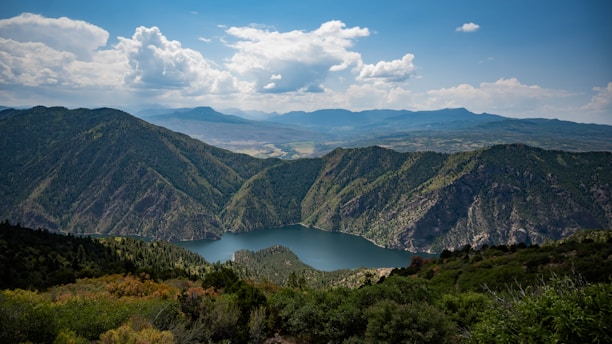 A picturesque view of a lake surrounded by lush greenery and hills.