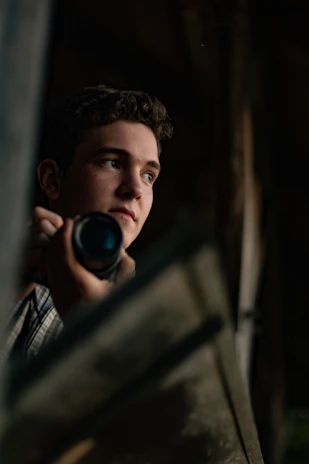 A cinematic still from a documentary video featuring a thoughtful subject in natural urbanscape lighting.