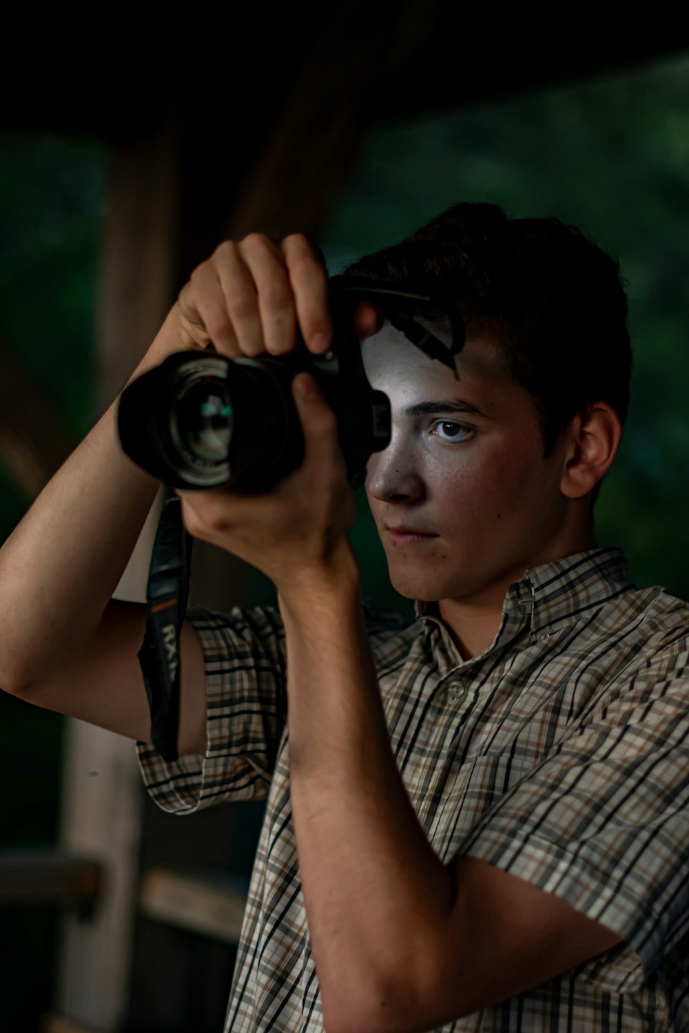 man in black and white plaid button up shirt holding black dslr camera