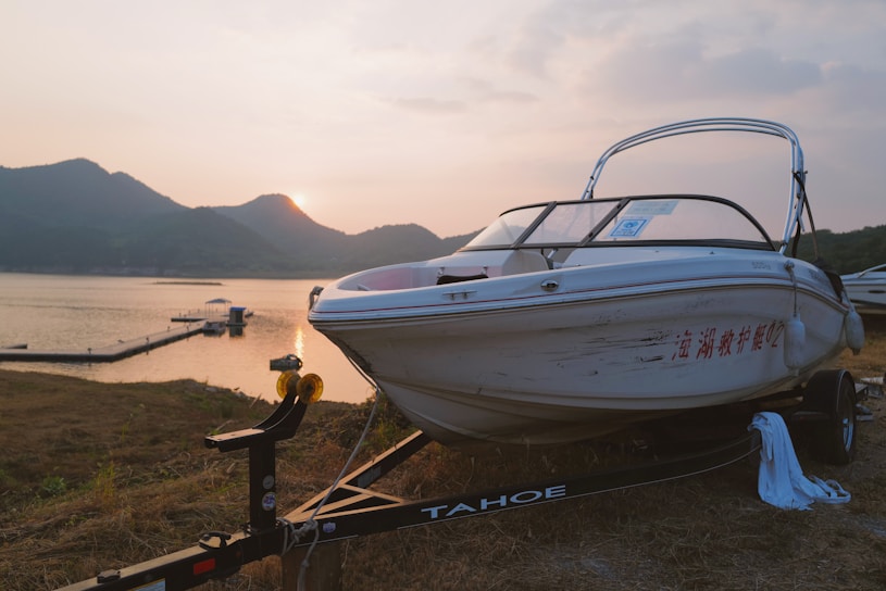 A sleek aluminum alloy boat trailer parked by a serene lakeside at sunset.