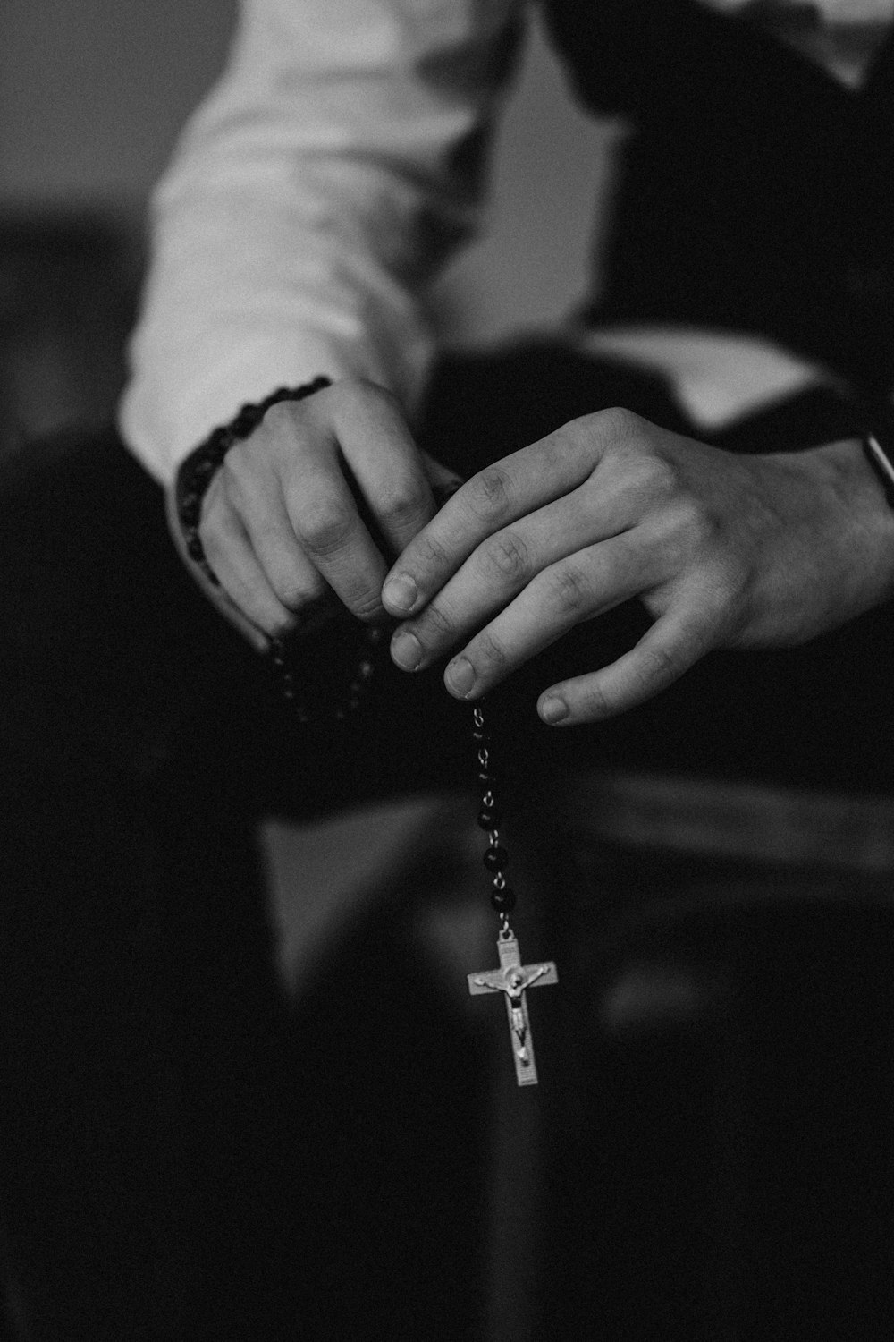 grayscale photo of person holding cross