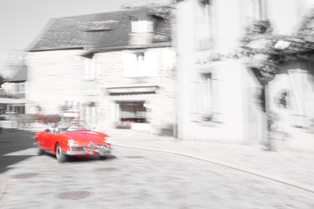 red car parked beside white building during daytime