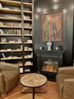 Cozy fireplace corner in the common lounge area with comfortable armchairs and books.