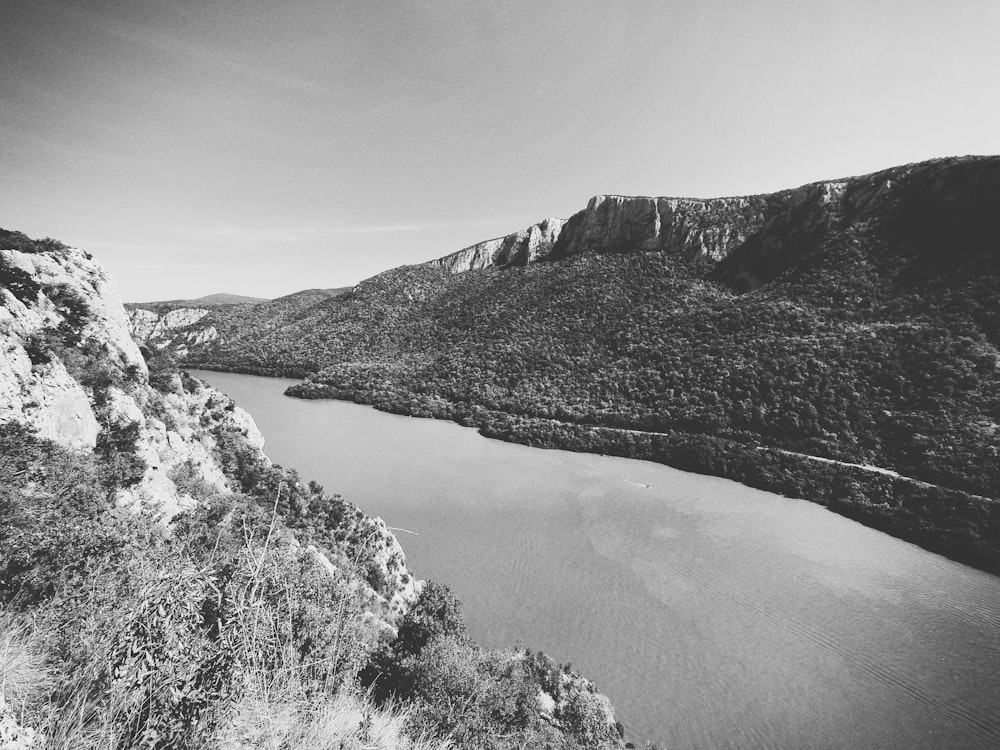 grayscale photo of river between mountains
