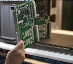 person holding green and black computer motherboard