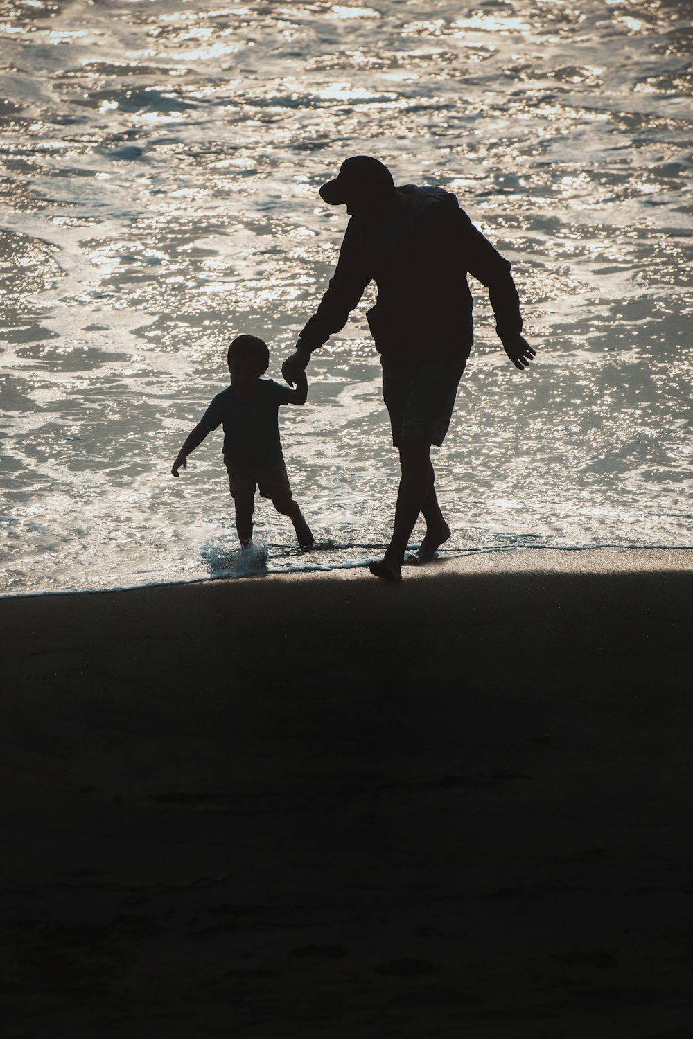 a person and a child walking on the beach