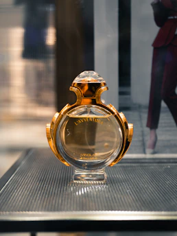 Close-up of a luxurious perfume bottle with golden accents on a minimalist black background.