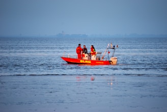 people riding red boat on sea during daytime