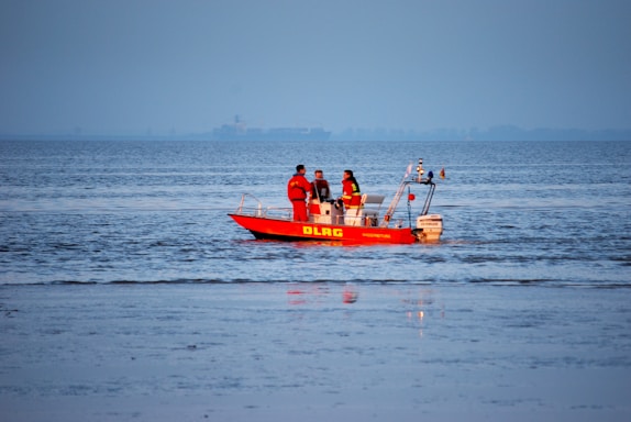 people riding red boat on sea during daytime