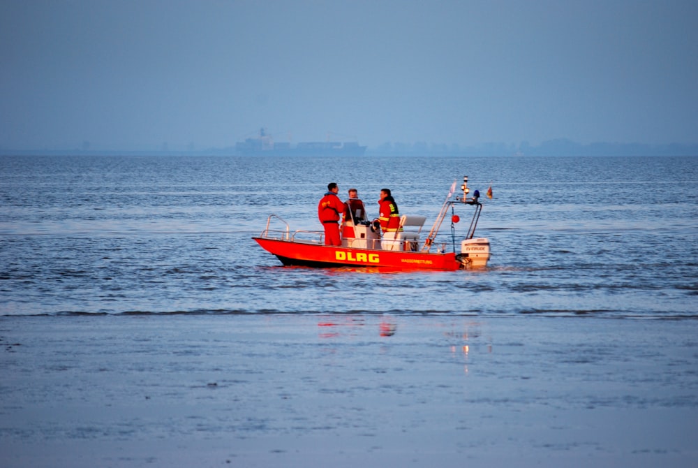 people riding red boat on sea during daytime