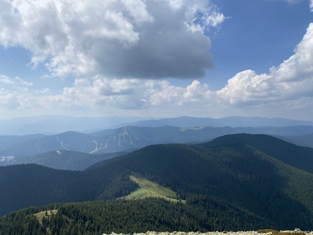 Grüne Berge tagsüber unter weißen Wolken