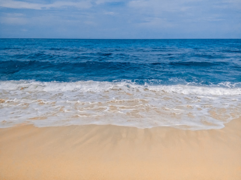 a sandy beach with waves coming in to shore