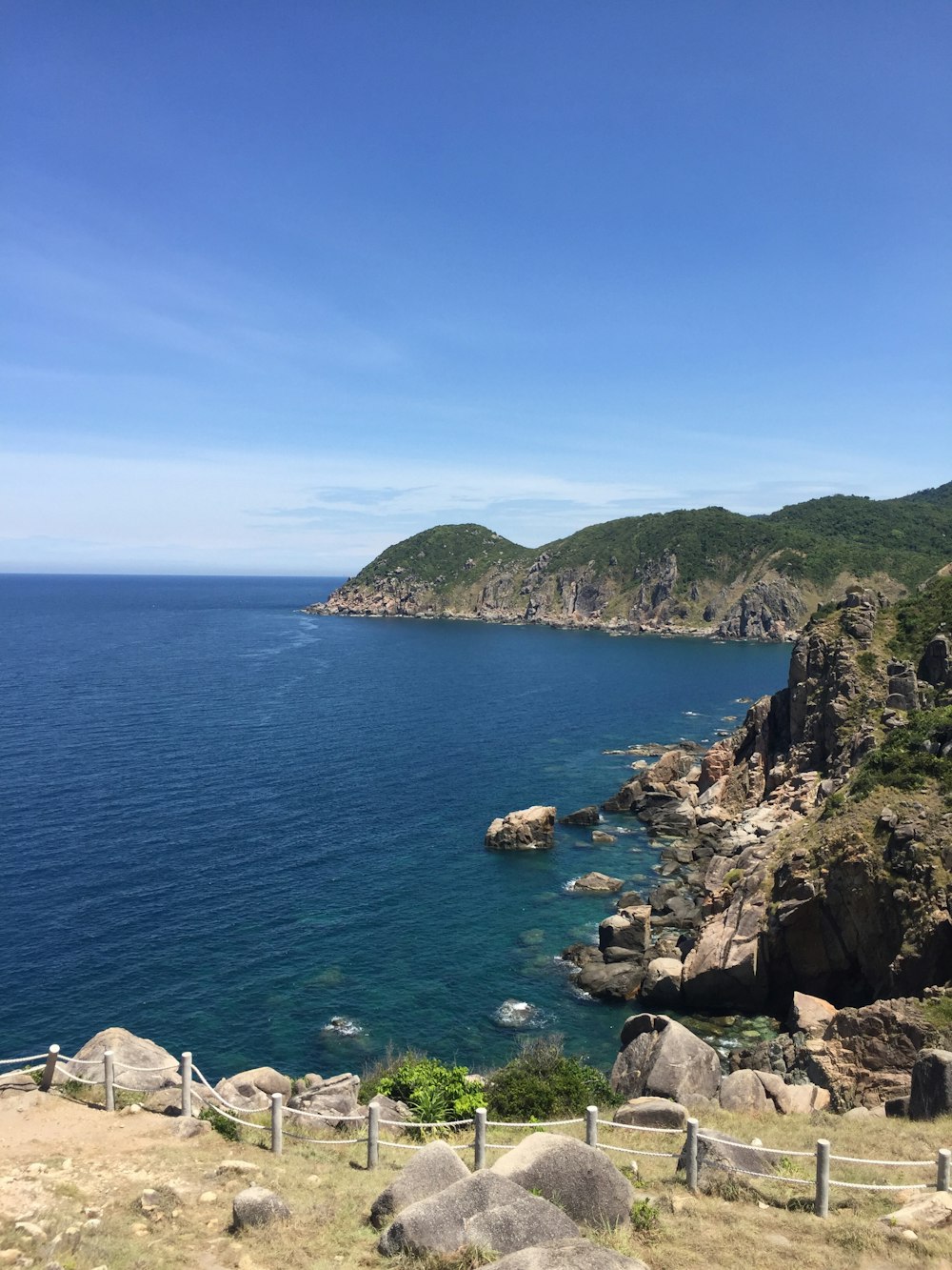 green and brown mountain beside blue sea under blue sky during daytime