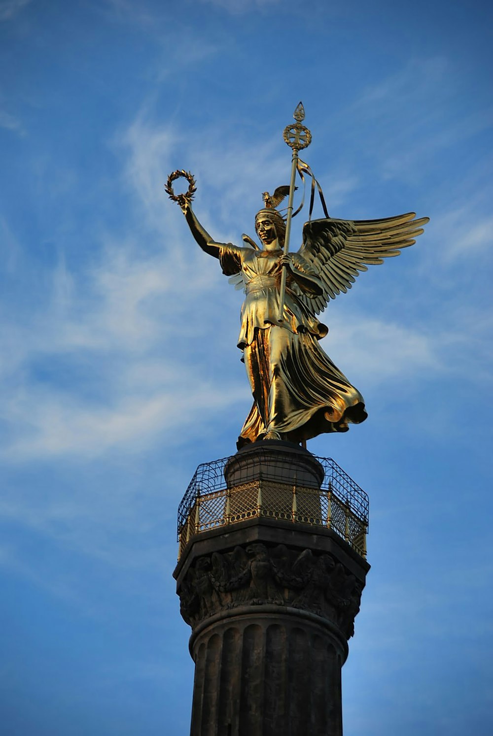 statua dell'angelo d'oro sotto il cielo blu durante il giorno