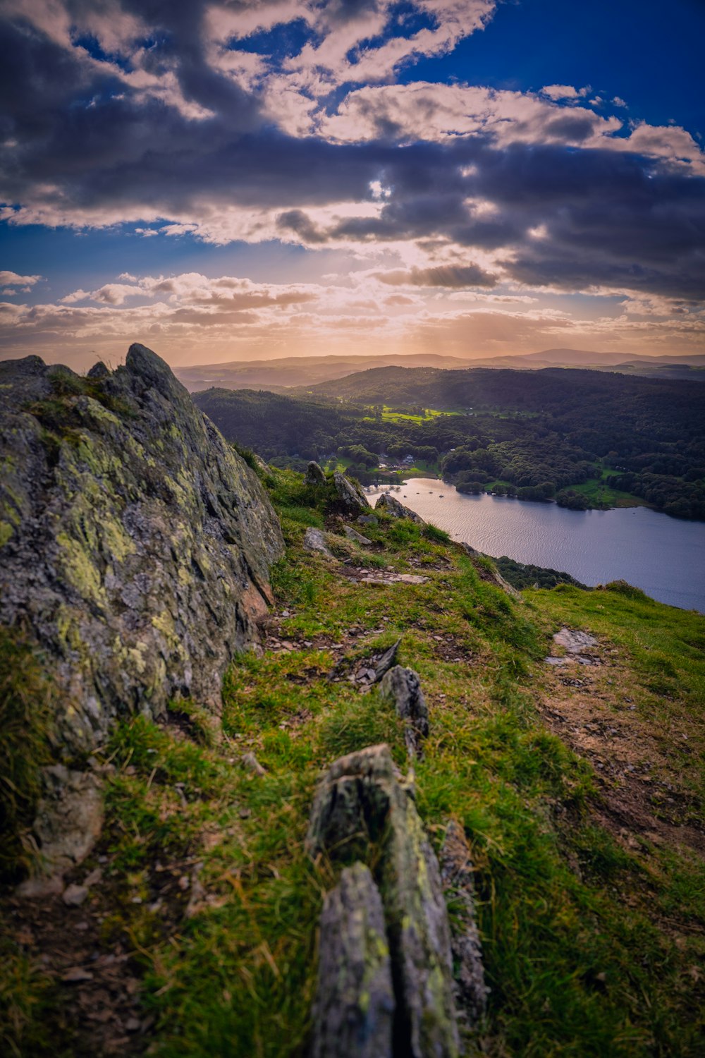 green grass covered mountain near lake under cloudy sky during daytime