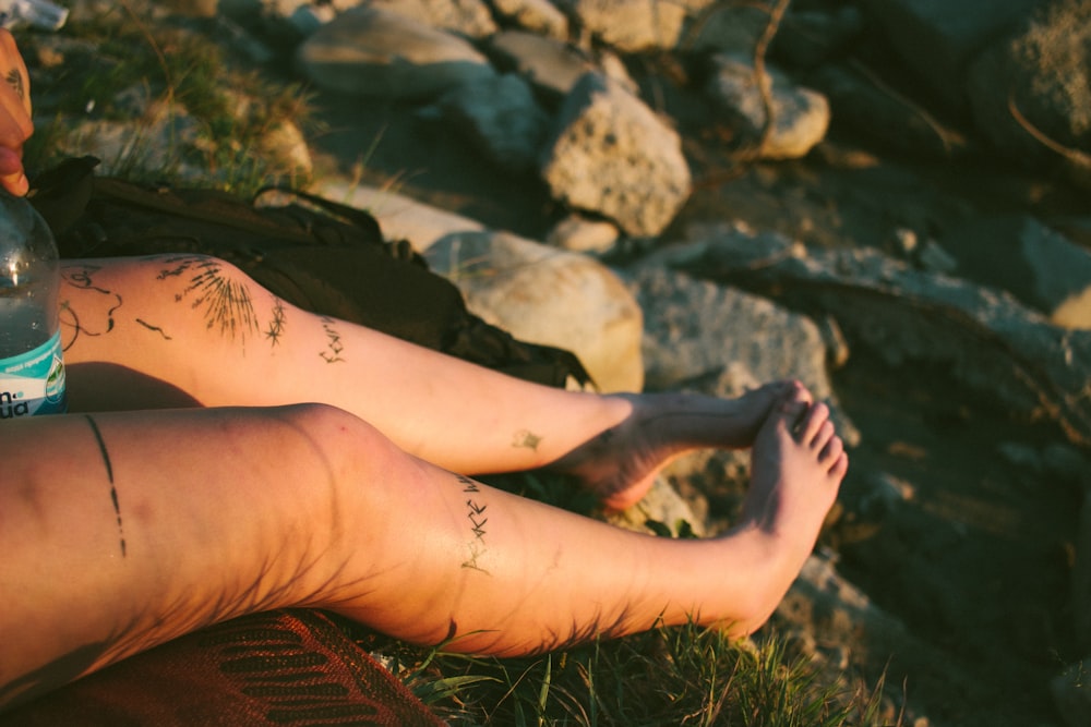 a person with tattoos on their legs sitting on the ground