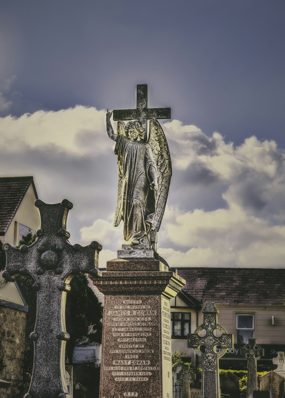 une statue d’une femme tenant une croix au sommet d’une tombe