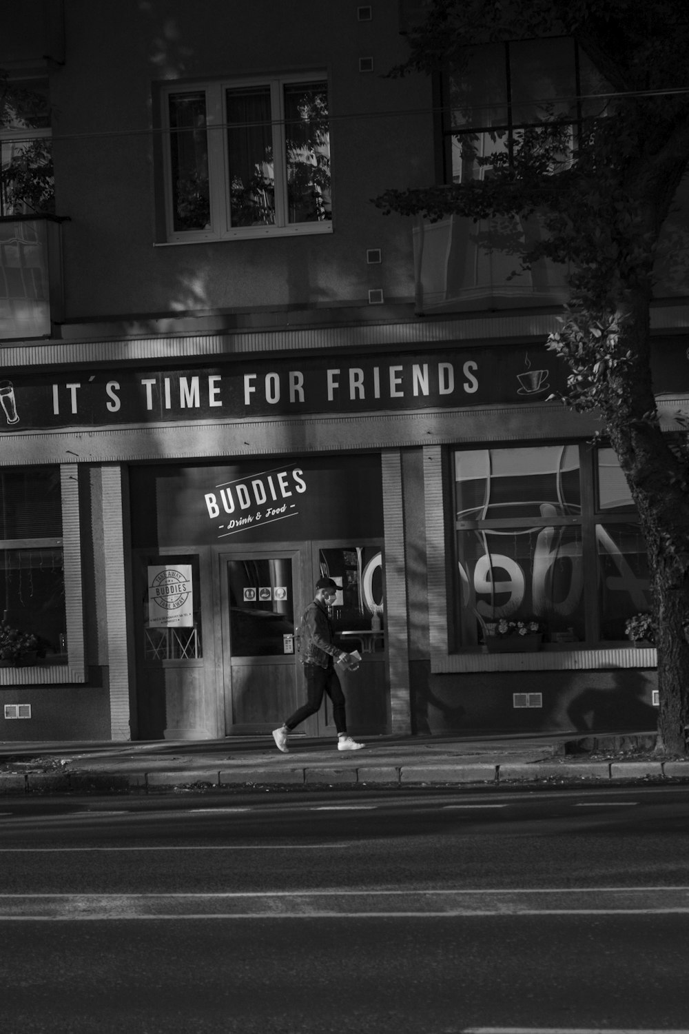 a black and white photo of a person walking in front of a store