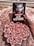 A person is holding a book titled 'Jack Hawthorne' by Ella Maise, which features a black and white portrait of a man on the cover. The background consists of a fluffy, pink textured surface. Beside the book, there is an arrangement of pink roses, creating a romantic and soft ambiance.