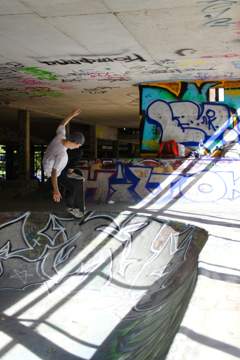 man in white shirt and gray pants standing on black and white graffiti wall