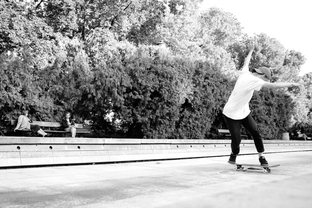 grayscale photo of woman in white long sleeve shirt and black pants walking on street