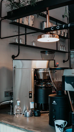 An inviting coffee corner setup featuring a modern espresso machine, ceramic mugs, and a small potted plant, bathed in natural morning light.