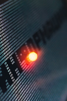 Binary code runs across a digital screen, highlighted by a glowing red-orange LED light. The numbers are aligned in a matrix pattern, creating a sense of digital complexity and data flow.
