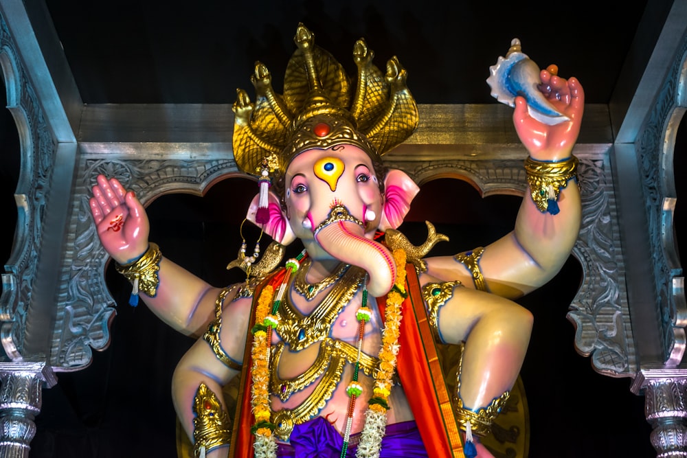 hindu deity statue in front of gold and purple wall