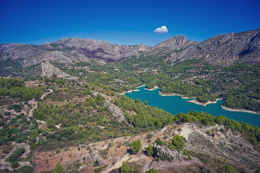 Montagnes vertes et grises près du lac sous le ciel bleu pendant la journée