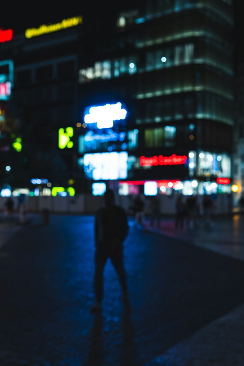 man in black pants walking on sidewalk during night time