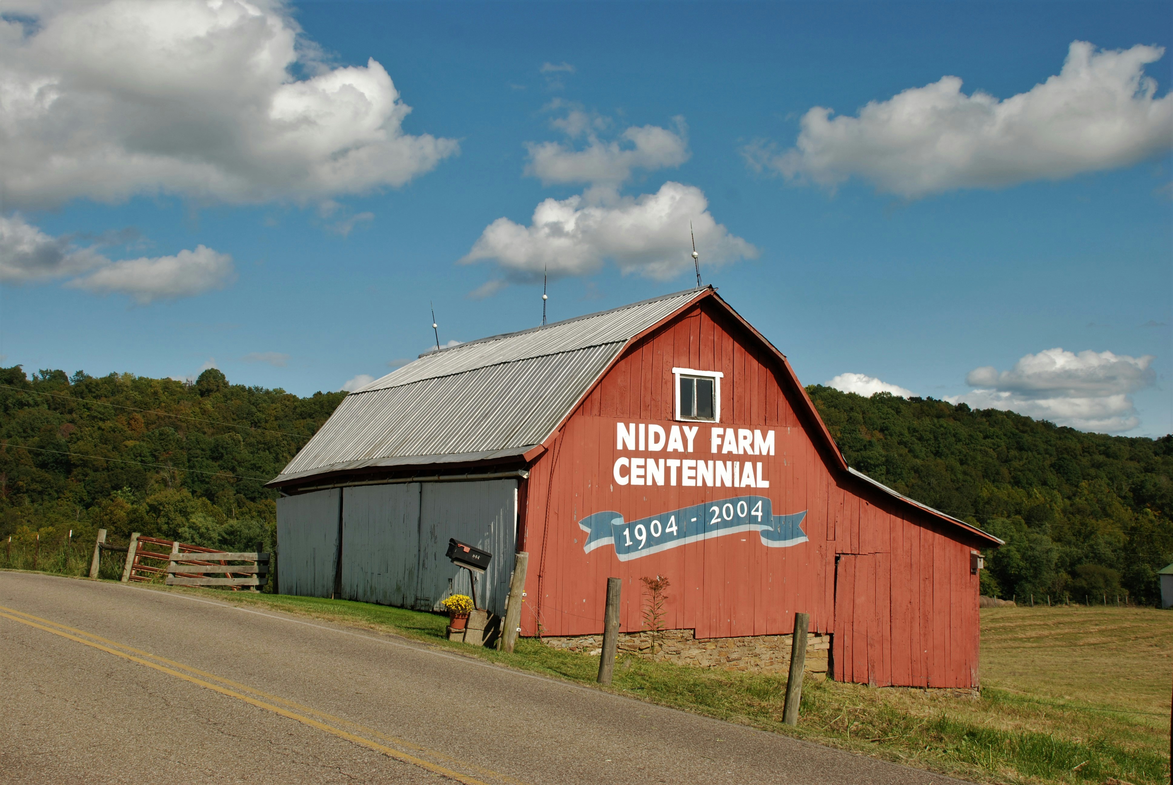 people walking on road near brown wooden barn under blue sky during daytime
