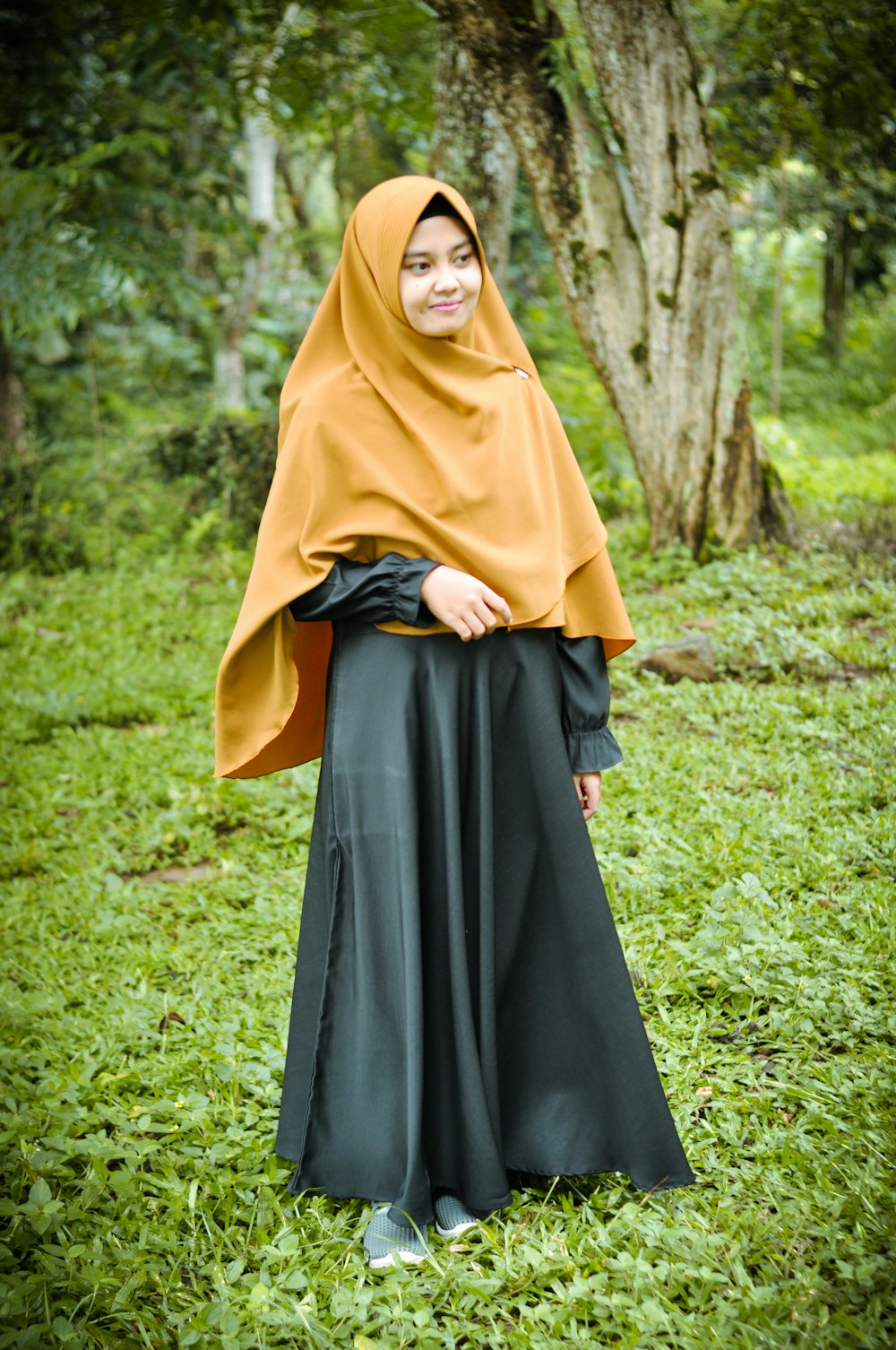 woman in brown hijab standing on green grass field