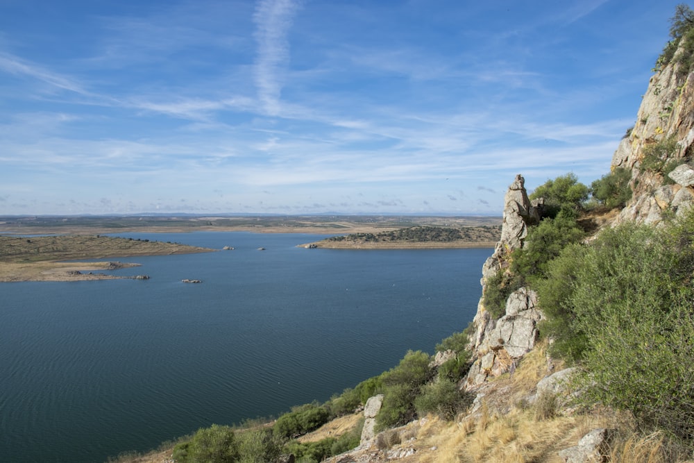 montanha rochosa marrom ao lado do mar azul sob o céu azul durante o dia