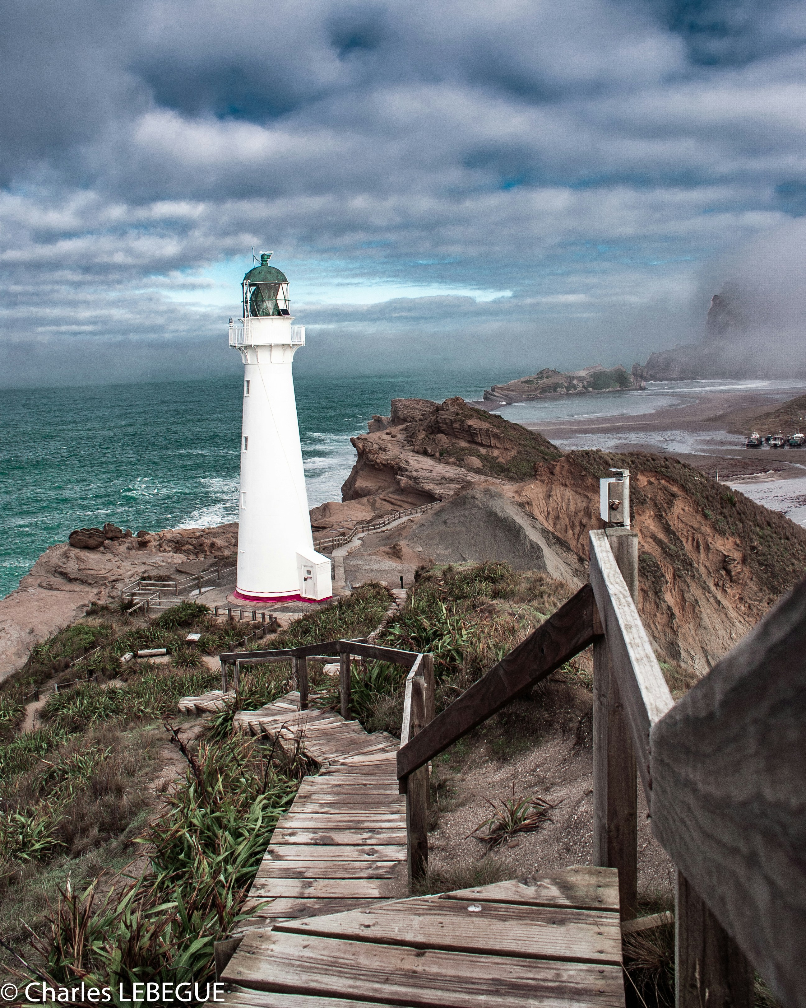 farol branco na montanha rochosa marrom sob o céu azul durante o dia