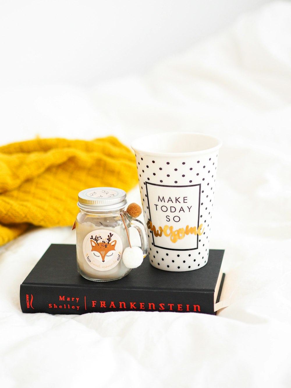 white and black ceramic mug beside white and black polka dot ceramic mug on black book