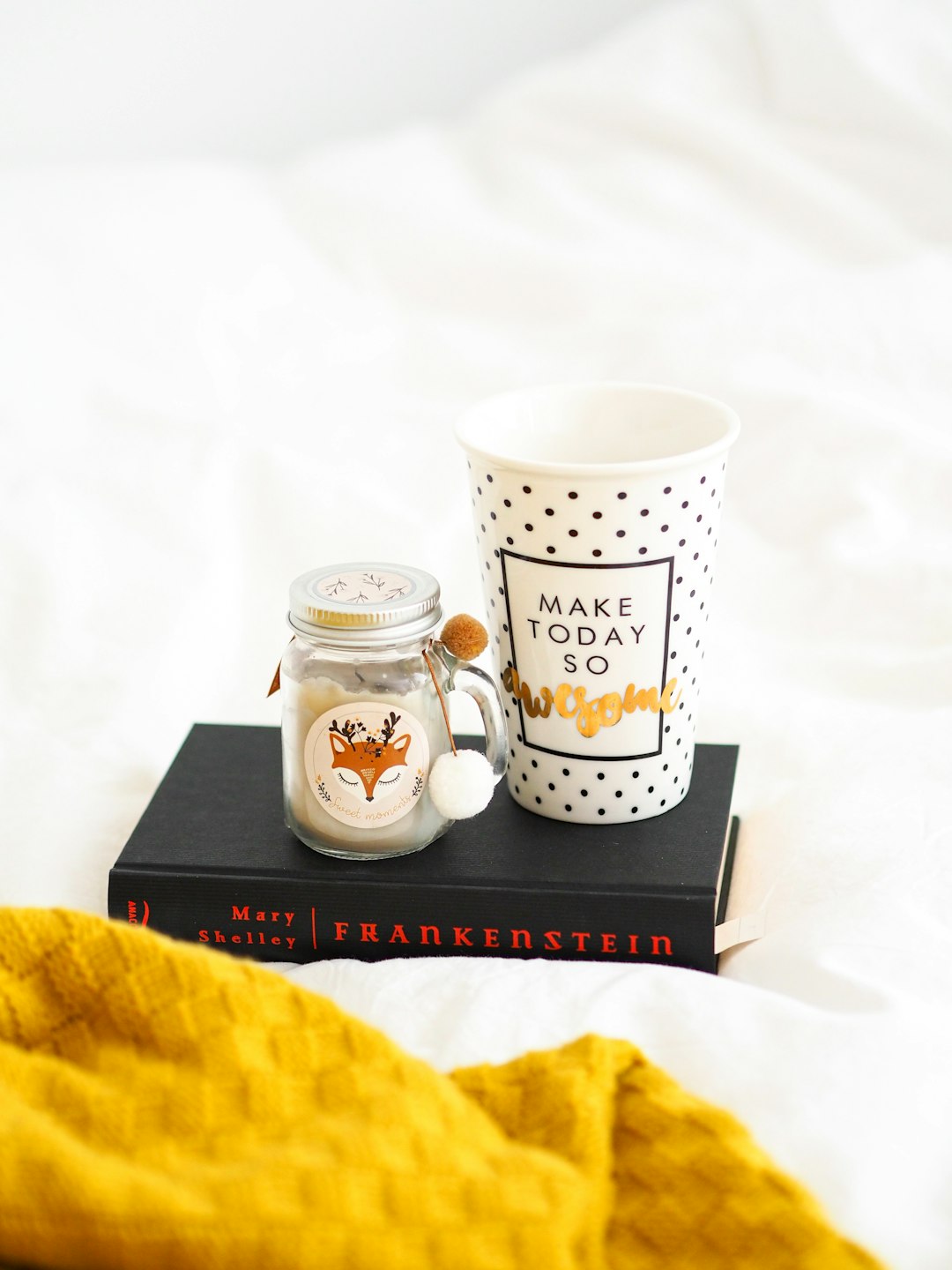 white and black ceramic mug beside white and black polka dot ceramic mug on black book