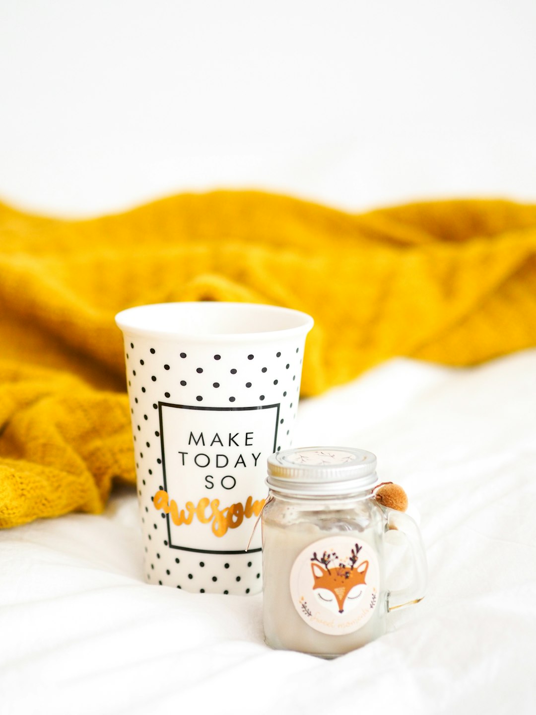 white and black polka dot ceramic mug beside clear glass jar with brown liquid inside