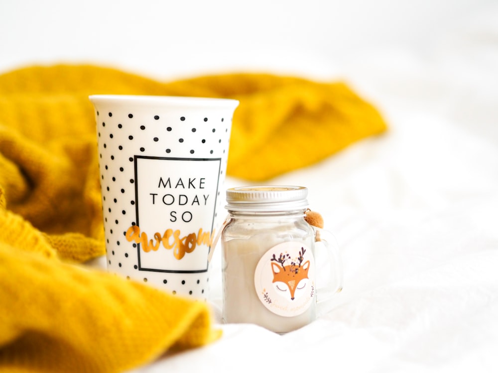 white and brown ceramic mug beside yellow textile