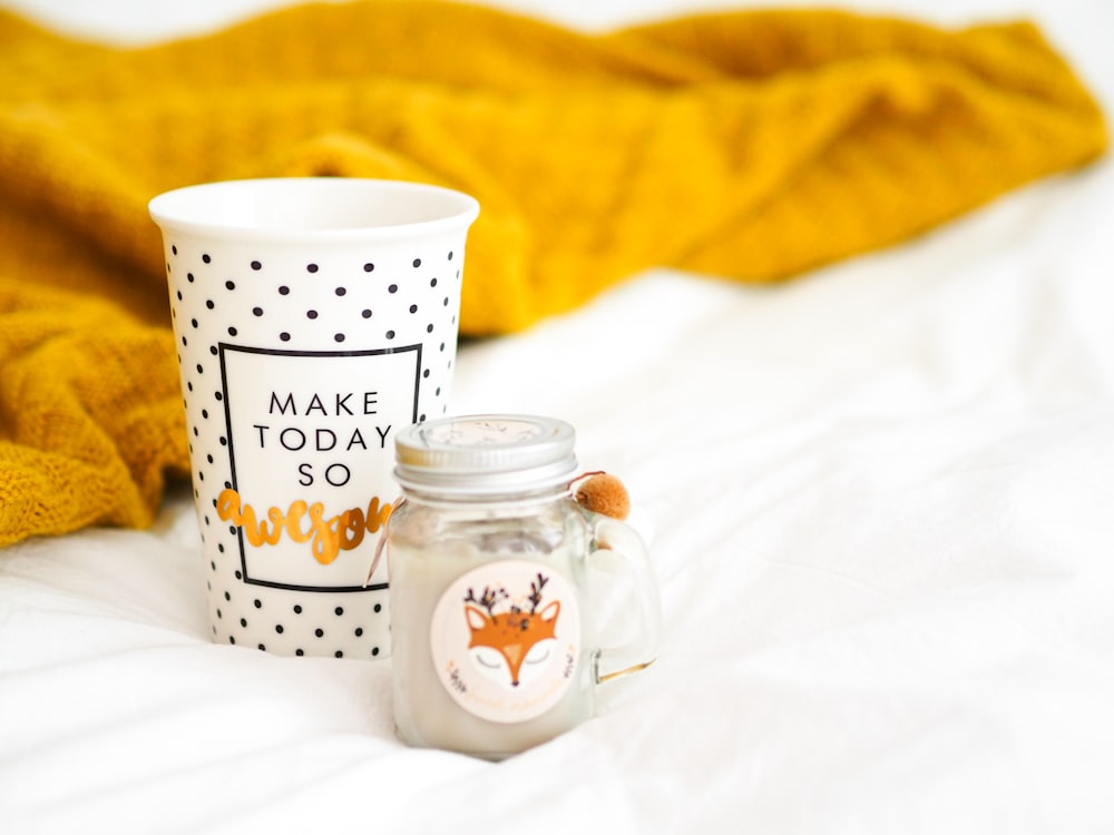 white and black polka dot ceramic mug beside clear glass jar with white and black polka