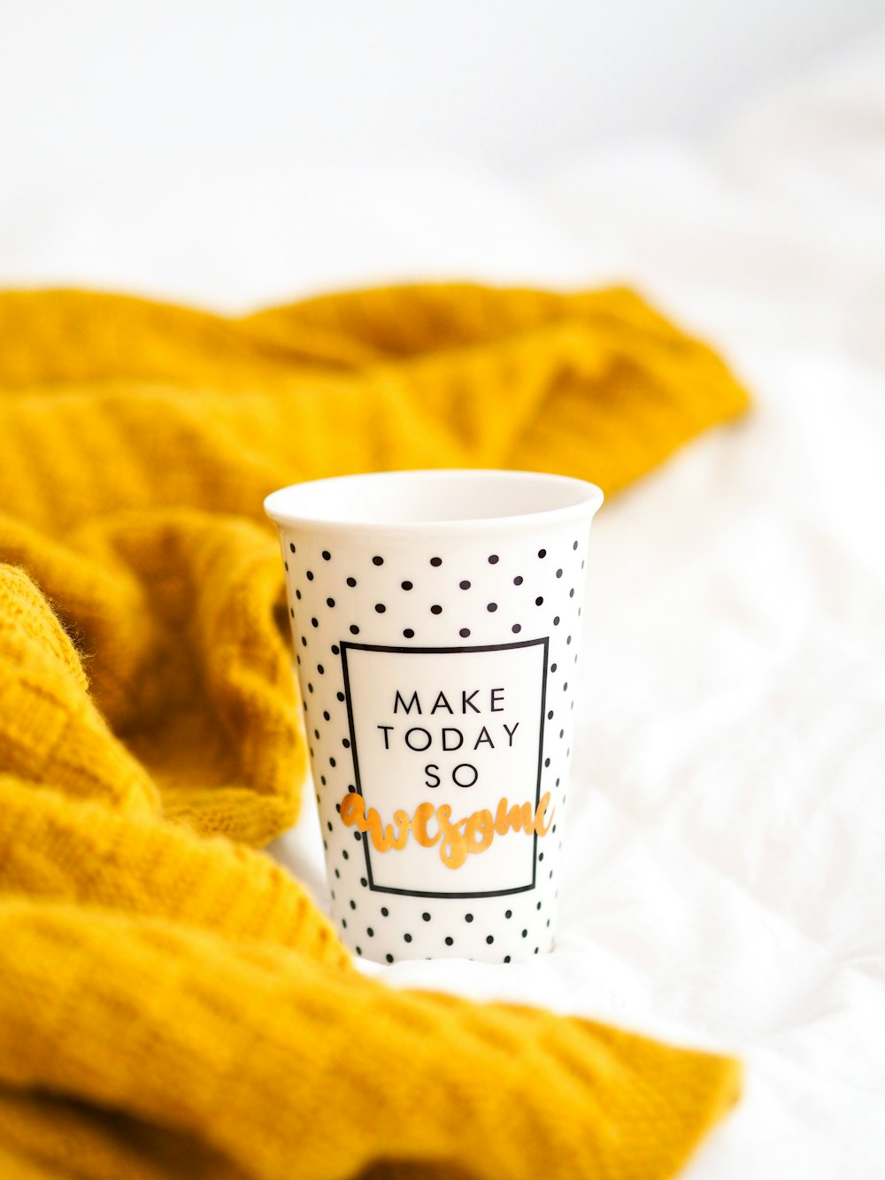 white and black polka dot ceramic mug beside yellow textile