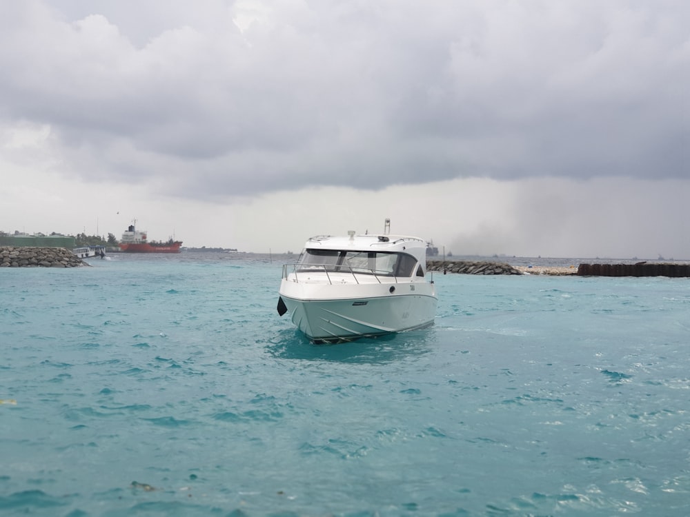 white and blue boat on sea under white clouds during daytime