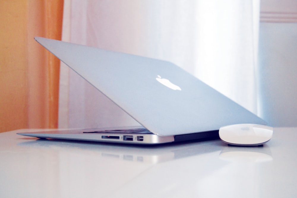 silver macbook on white table