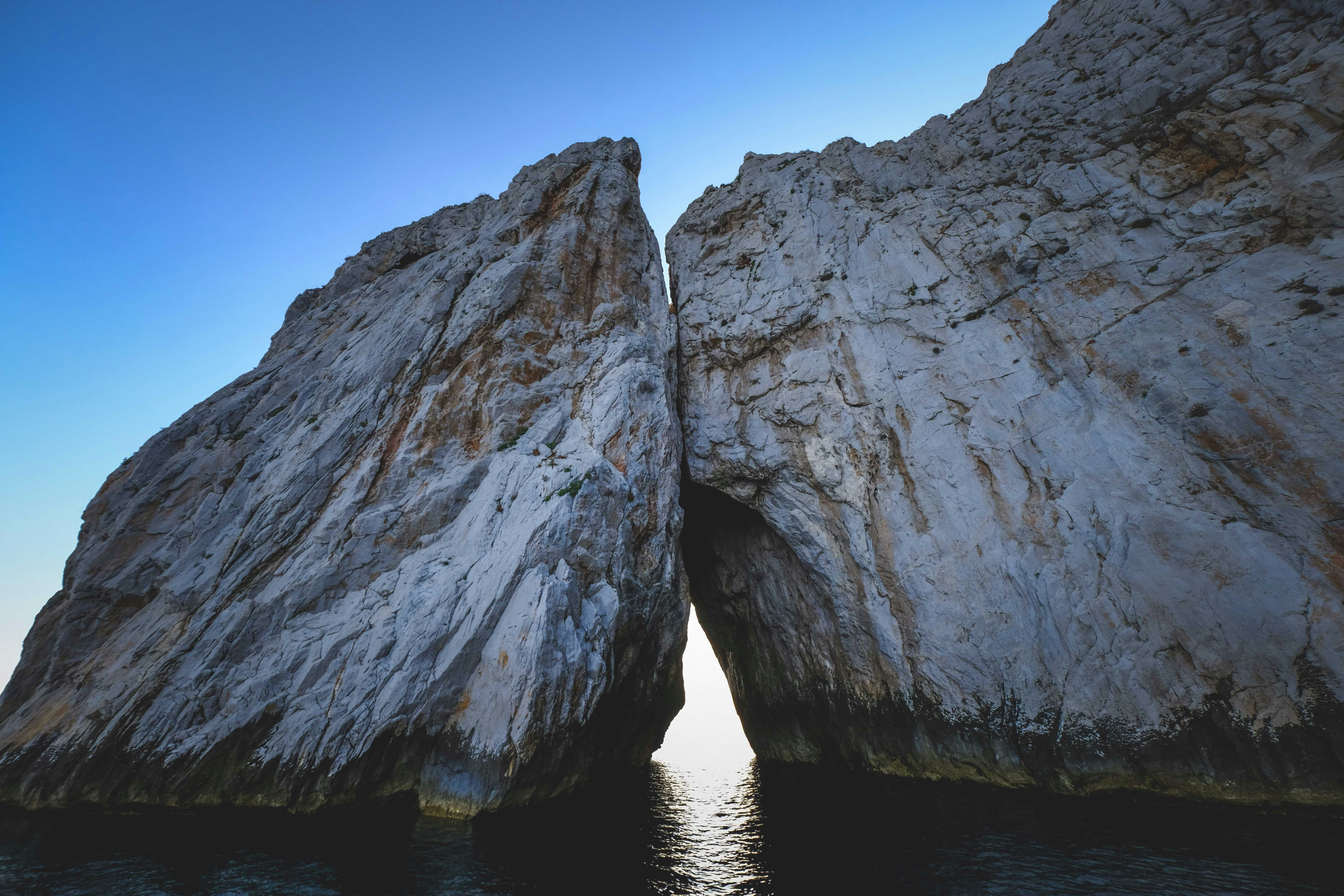 gray rock formation on body of water during daytime
