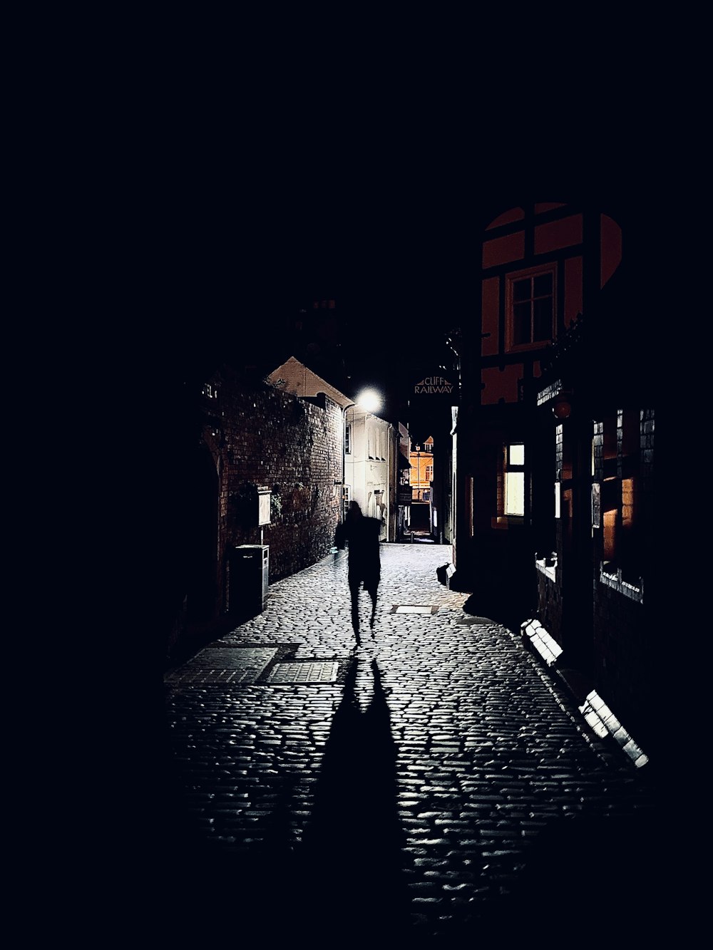 a person walking down a cobblestone street at night